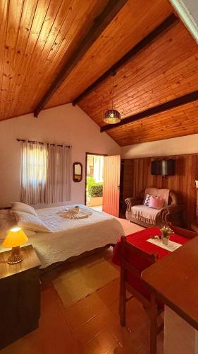 a bedroom with a large bed and a table at Chalés Raios de Sol in Monte Verde