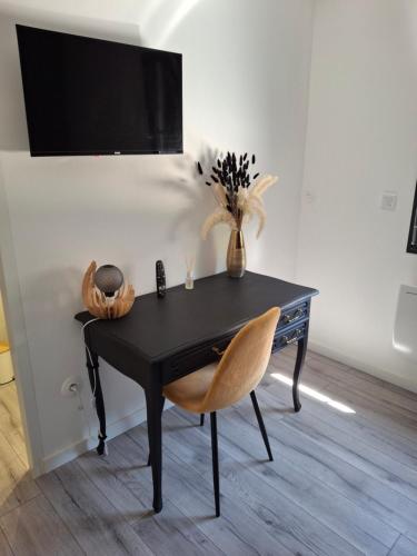 un bureau noir avec une chaise et un vase de fleurs dans l'établissement La maison d'à côté Chambre 1, à Cuise-la-Motte