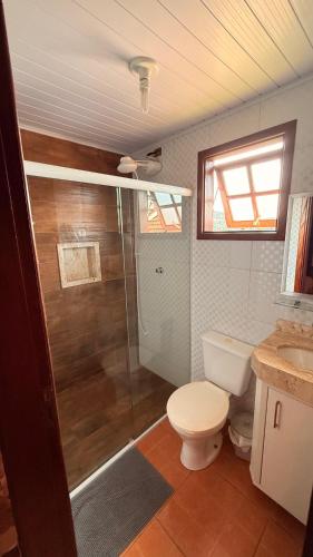 a bathroom with a toilet and a shower and a sink at Chalés Raios de Sol in Monte Verde