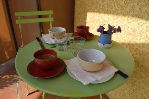 une table verte avec des bols et des tasses dessus dans l'établissement Chambre la canauloise, à Canaules-et-Argentières