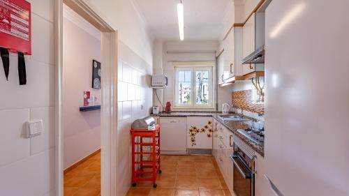 a small kitchen with white cabinets and a red ladder at Marquinhos do Mar by AcasaDasCasas in Ericeira