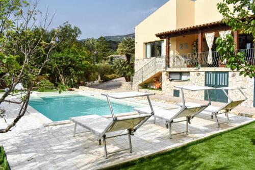 a villa with a pool and two chairs and a house at La Villa Incantata in Poggio Dei Pini
