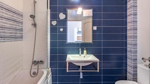 a blue tiled bathroom with a sink and a mirror at Marquinhos do Mar by AcasaDasCasas in Ericeira