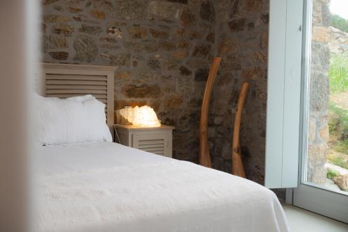 a bedroom with a bed and a stone wall at The Summit of Mykonos in Kalo Livadi