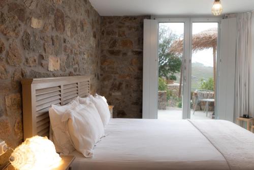a bedroom with a bed with a stone wall at The Summit of Mykonos in Kalo Livadi