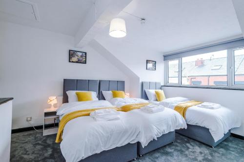 um quarto com duas camas e uma janela em Spacious 5 bedroom house near Leeds City Centre sleeps 12 suits contractors with free parking em Hunslet