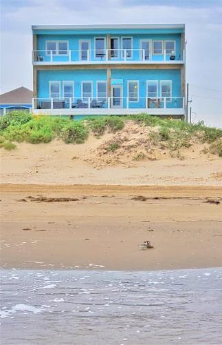 a blue building on top of a beach at Beachfront - Hot Tub - Home Theater in Bolivar Peninsula