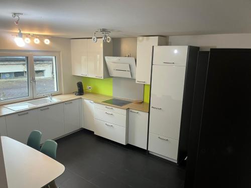 une cuisine avec des armoires blanches et un réfrigérateur noir dans l'établissement Süße Marie Rüppurr Apartment 1, à Karlsruhe