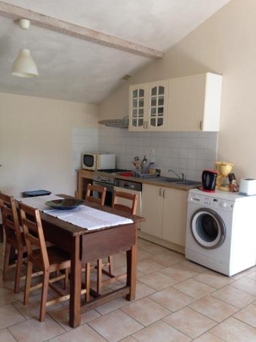 une cuisine avec une table et une machine à laver dans l'établissement Gite 4 couchages piscine privée, à Roquecor