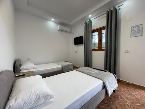 a room with two beds and a tv at PANORAMIC VIEW Xhanari Guesthouse Tepelene in Tepelenë