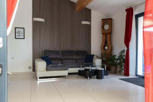 a living room with a black couch and a clock at L'ESCALE COTE BLEUE VILLA & Spa Classée 4 Étoiles in Sausset-les-Pins