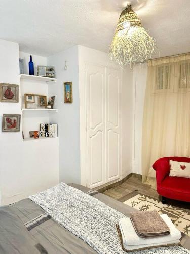 a bedroom with a bed and a red chair at Des appartements a la Marsa plage Pieds dans l'eau in Dar Salah Bey