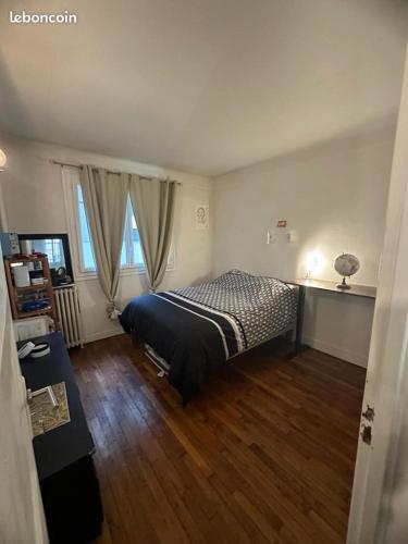 une chambre avec un lit et un parquet dans l'établissement Pièce principale dans T2 tout équipé, 1ier étage, entrée-sortie libre, à Colombes
