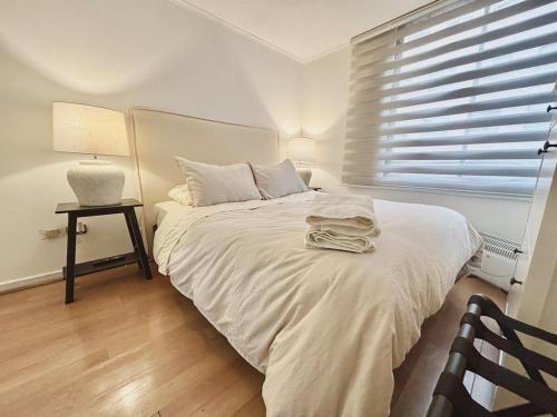 Una cama blanca en una habitación con ventana. en Steps to Costanera Center & Metro, en Santiago