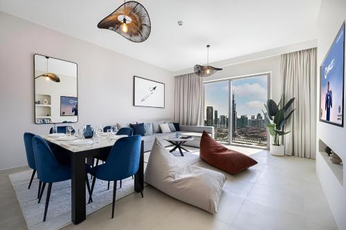 a living room with a dining room table and blue chairs at Dubai Mall Connection - Burj Views - Turf Balcony in Dubai