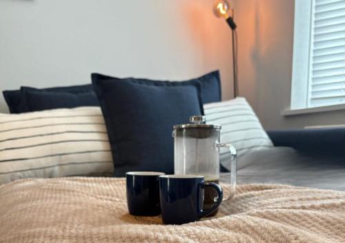 two coffee mugs on a bed with a juicer at Modern Coastal Retreat HotTub FirePit SkyTV in Lymington