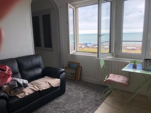 - un salon avec un canapé en cuir noir et des fenêtres dans l'établissement cocon marin, à Dieppe