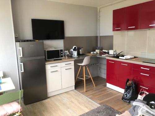 - une cuisine avec des placards rouges et un réfrigérateur noir dans l'établissement cocon marin, à Dieppe