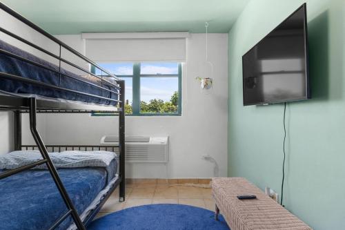 a bedroom with a bunk bed and a flat screen tv at Paradise at Aquatika Poolfront with Private Beach in Vieques