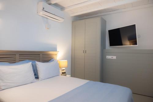 a bedroom with a white bed and a tv at The Summit of Mykonos in Kalo Livadi