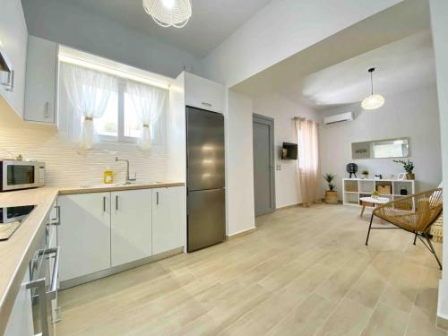 a kitchen with white cabinets and a living room at Bamboo House Syros No1 in Ermoupoli