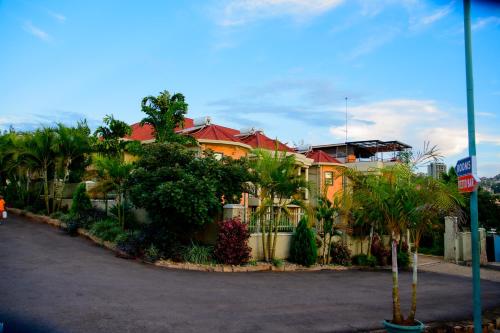 a large yellow house with palm trees in front of it at Quality Inn Hotel Kigali in Kigali