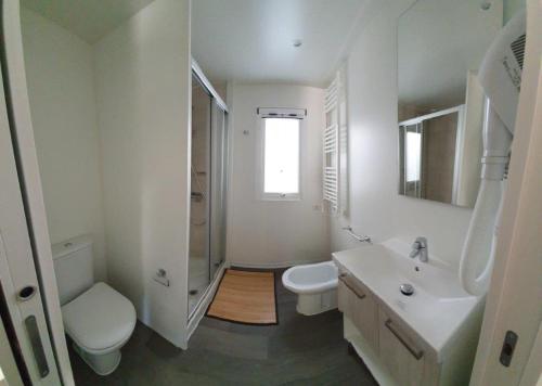a white bathroom with a toilet and a sink at Camping Al Lago Ledro in Ledro
