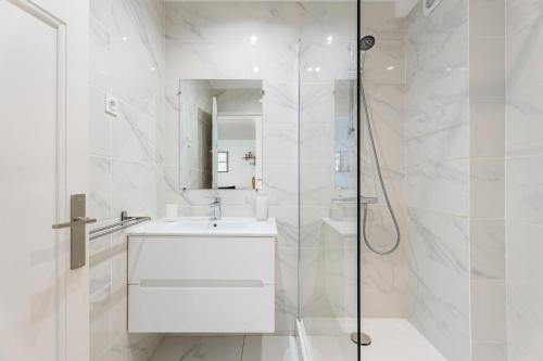 une salle de bain blanche avec un lavabo et une douche dans l'établissement Superbe Appartement Moderne, Prado,à Deux Pas du Vélodrome, à Marseille