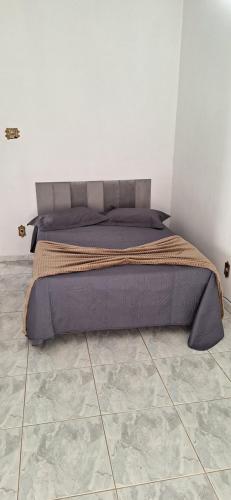 a bed in a bedroom with a white wall at Casa Temporada em Aparecida com vista para Basílica in Aparecida