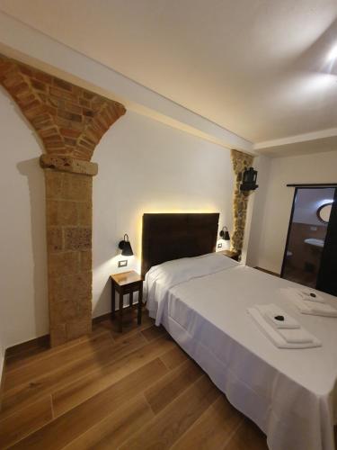 a bedroom with a white bed and a brick wall at L'Alberghetto Le Dimore Di Contrasti in Castiglione dʼOrcia