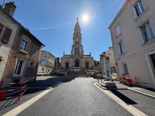 une église avec une haute tour au milieu d'une rue dans l'établissement Appartement cosy à deux pas de la cathédrale, à Reims