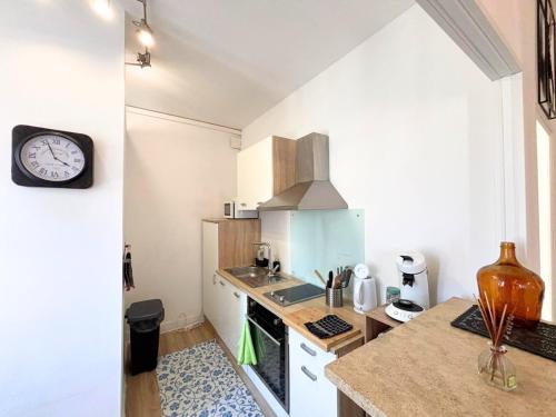 une cuisine avec un comptoir et une horloge au mur dans l'établissement Appartement cosy à deux pas de la cathédrale, à Reims
