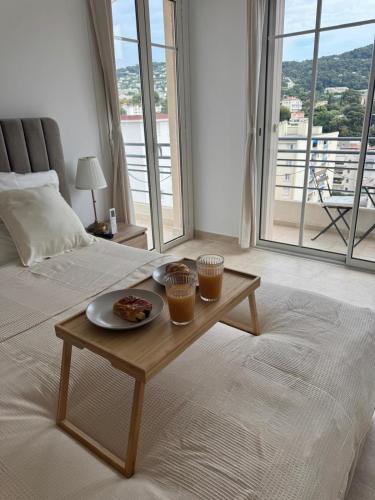 a room with a table with a plate of food on a bed at Magnifique T2 avec grande terrasse in Le Cannet