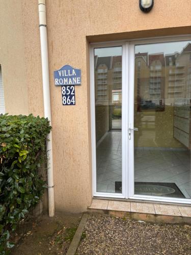 une porte en verre d'un bâtiment avec un panneau sur celui-ci dans l'établissement Appartement proche mer, à Cucq