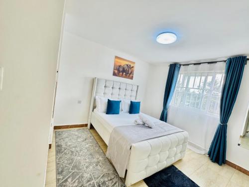 a bedroom with a white bed with blue pillows at Palazzo serenity in Ongata Rongai 