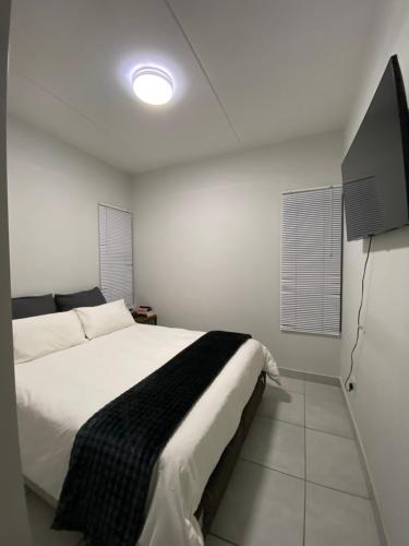 a bedroom with a bed and a flat screen tv at Elegant escape in Krugersdorp