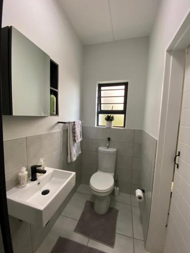 a bathroom with a white toilet and a sink at Elegant escape in Krugersdorp