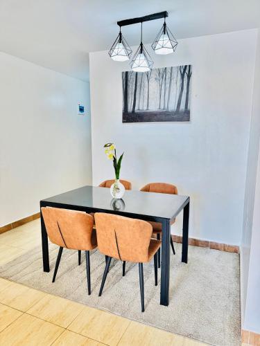 a black dining room table with orange chairs at Palazzo serenity in Ongata Rongai 