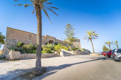 a building with palm trees and cars parked in a parking lot at Townhouse Ses Passadores in Porreres