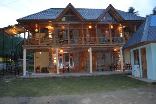 a large wooden house with a large deck at Freebird Nest Retreat in Jibhi