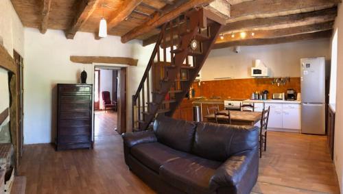 a living room with a leather couch and a kitchen at Maison calme avec jardin à Gramat in Gramat
