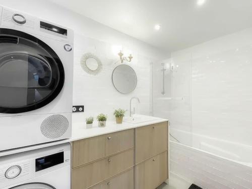 une salle de bain blanche avec une machine à laver et un lavabo dans l'établissement Charmante maison, 8 personnes, piscine et tennis, à Deauville