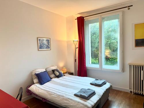 a bedroom with a bed and a window with red curtains at Villa arborée aux Portes de Paris in Bobigny