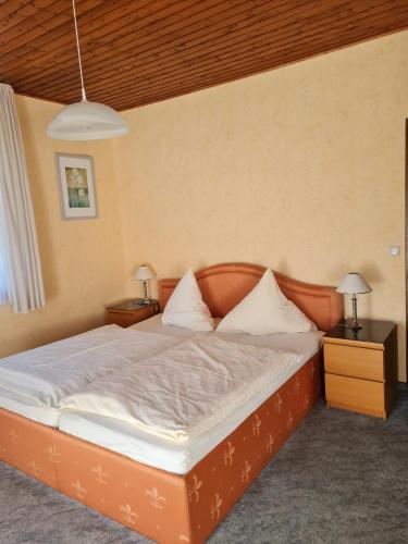 a bed in a room with two night stands and two lamps at Waldpension Rabeneck in Waischenfeld