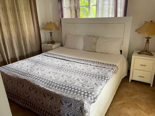 Un dormitorio con una cama blanca con dos mesitas de noche. en Villa Amour, en Sosúa