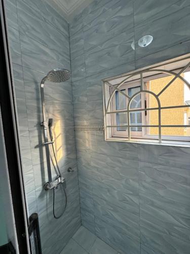 a shower with a glass door and a window at Cozy Apartment In East Legon Room 4008 in Accra