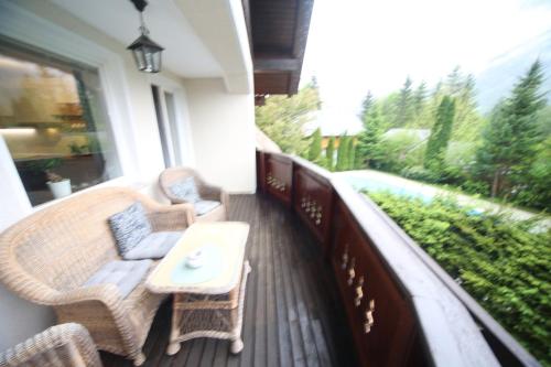 a balcony with wicker chairs and a table on a porch at Vila Edelweiss Rooms&App Kranjska Gora in Kranjska Gora
