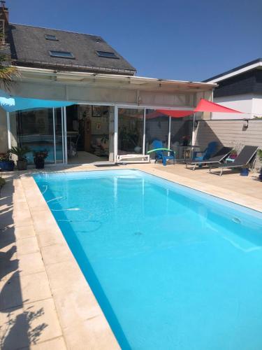 une grande piscine bleue à côté d'une maison dans l'établissement La vague salée, à Hermanville-sur-Mer