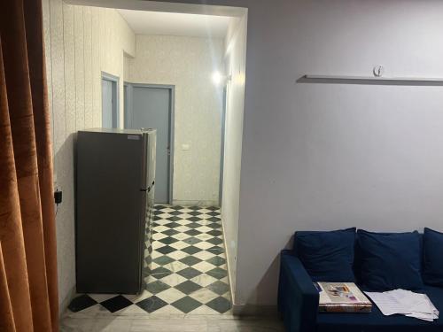 a living room with a blue couch and a checkered floor at Golden Triangle in Jāmb