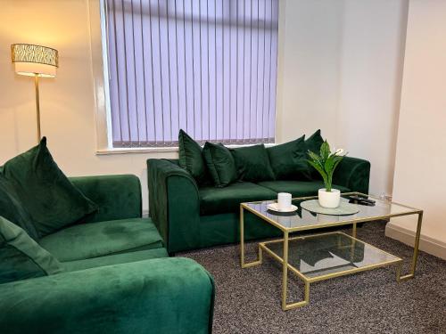 a living room with two green couches and a table at Hambledon House 4BR Entire Home in Middlesbrough